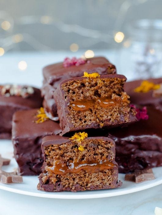 Lebkuchen cookie squares filled with plum jam and coated in chocolate on a plate.