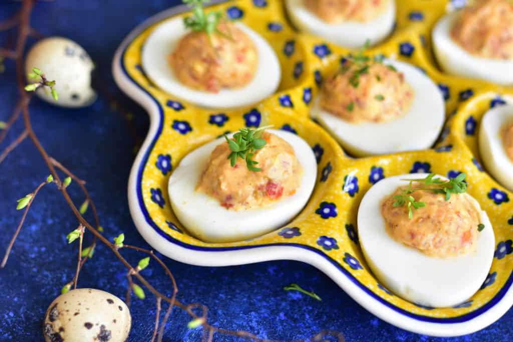 Sun-dried tomato deviled eggs in a yellow-blue serving dish.
