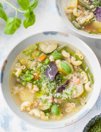Soupe au pistou in a blue bowl garnished with basil leaves.
