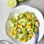 avocado egg salad in a white bowls, limes and coriander in the background