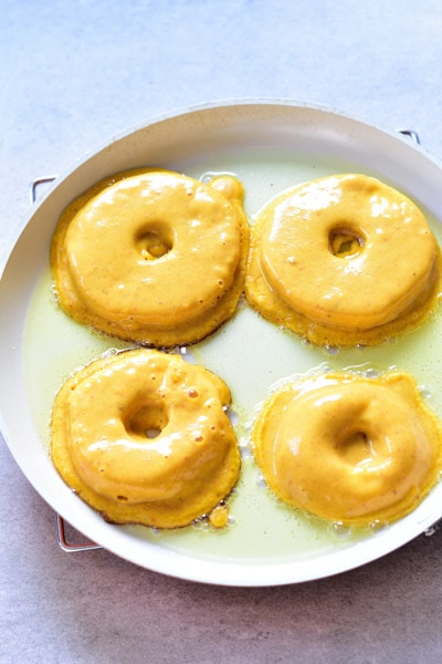 apple ring pancakes are being cooked on a pan