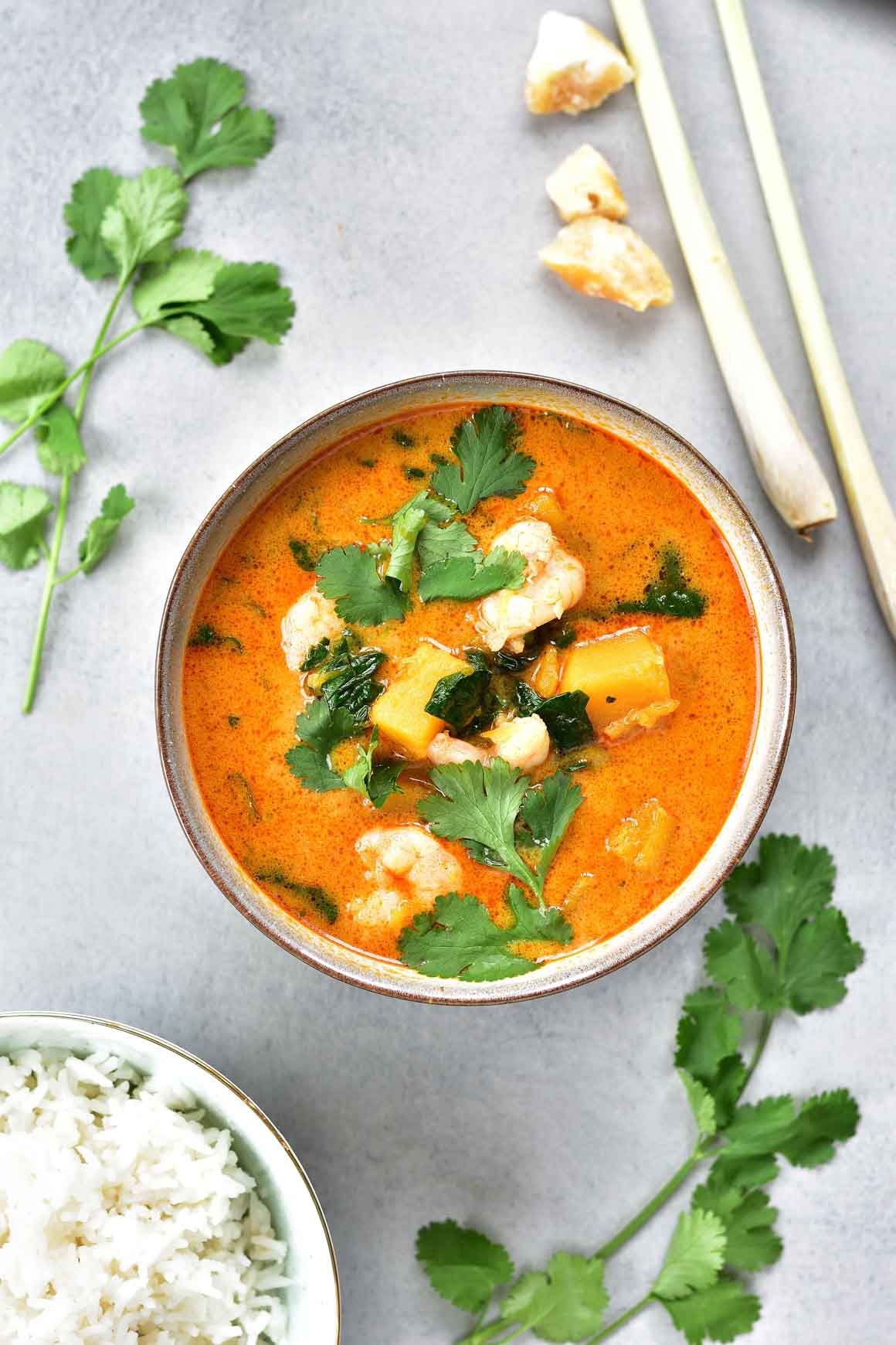Thai red curry with shrimp and spinach in a grey bowl.