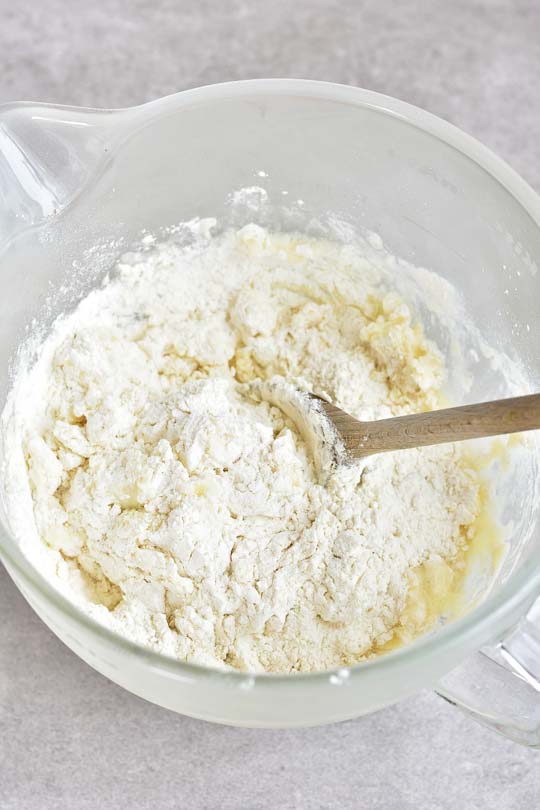 pierogi dough ingredients are being mixed with a wooden spoon