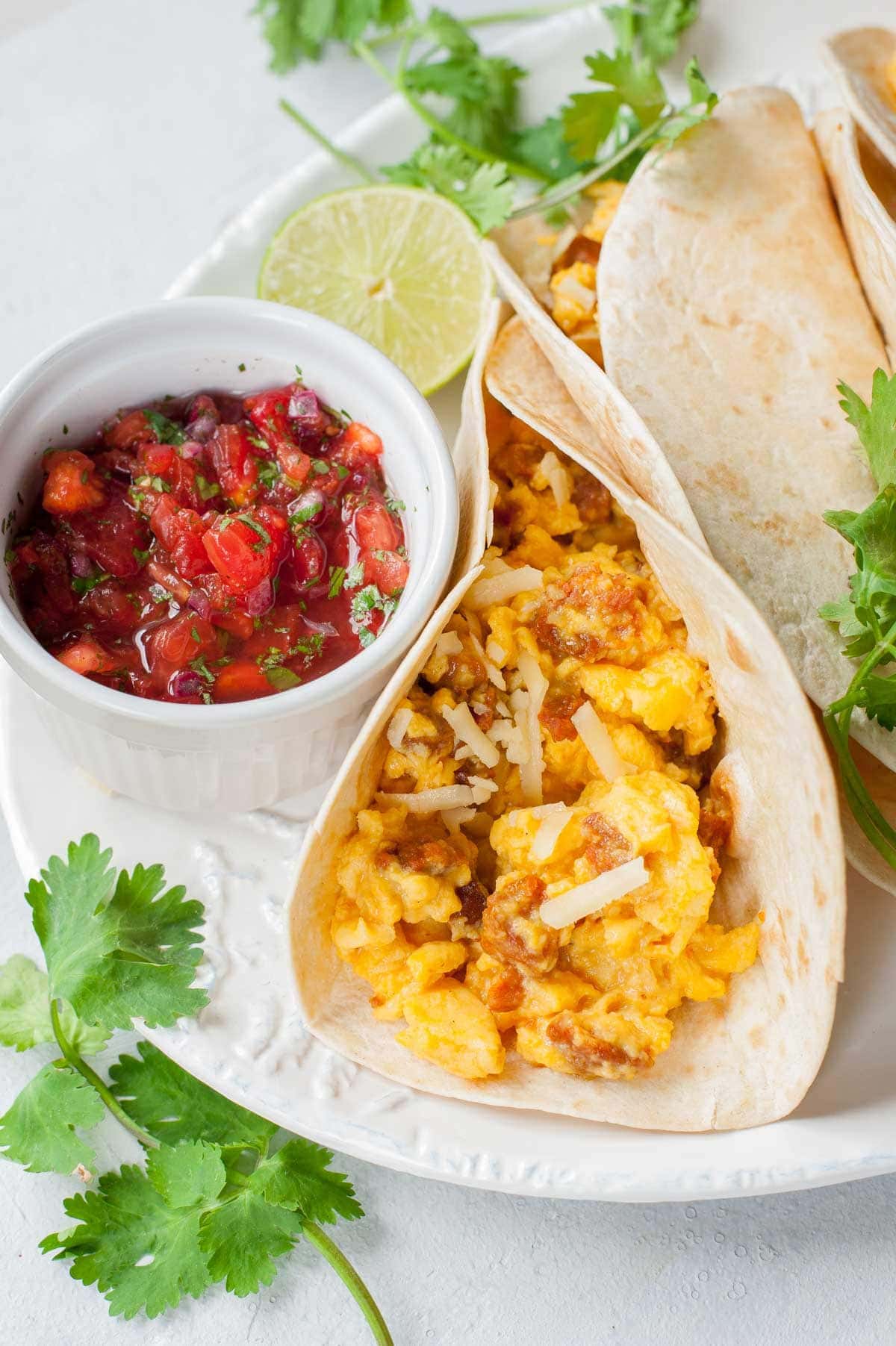 Scrambled eggs tacos with pico de gallo salsa on a plate.