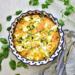 Smoked salmon frittata with zucchini and spinach in a white-blue baking dish.
