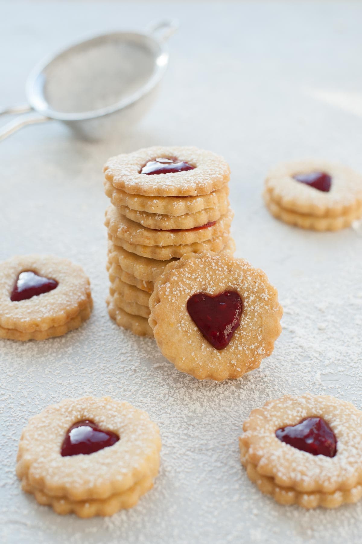 A stack of Linzer cookies filled with raspberry jam.