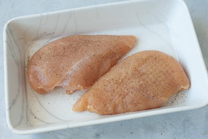 Two chicken breasts in a white baking dish.