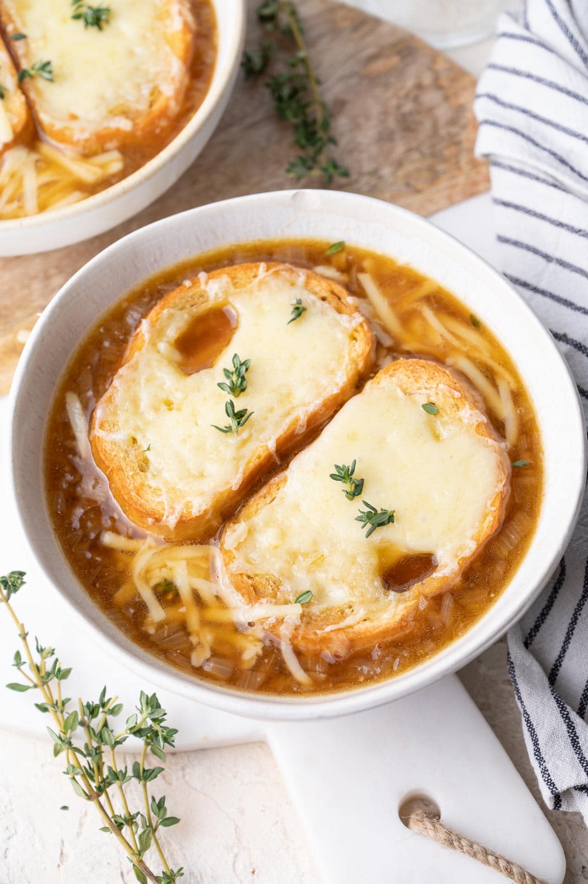 French onion soup topped with cheesy bread in a white bowl.