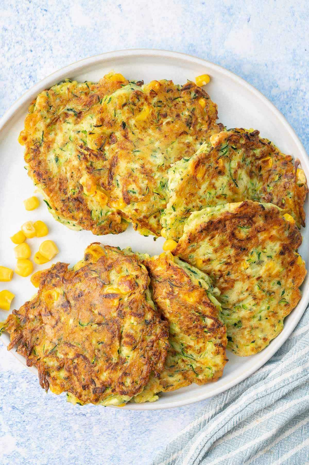 Zucchini corn fritters on a white plate.