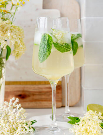 Two glasses with hugo cocktail. Elderflowers in the background.