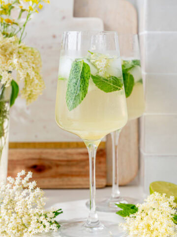 Two glasses with hugo cocktail. Elderflowers in the background.
