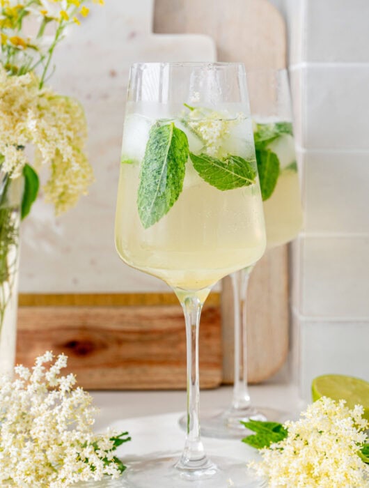 Two glasses with hugo cocktail. Elderflowers in the background.
