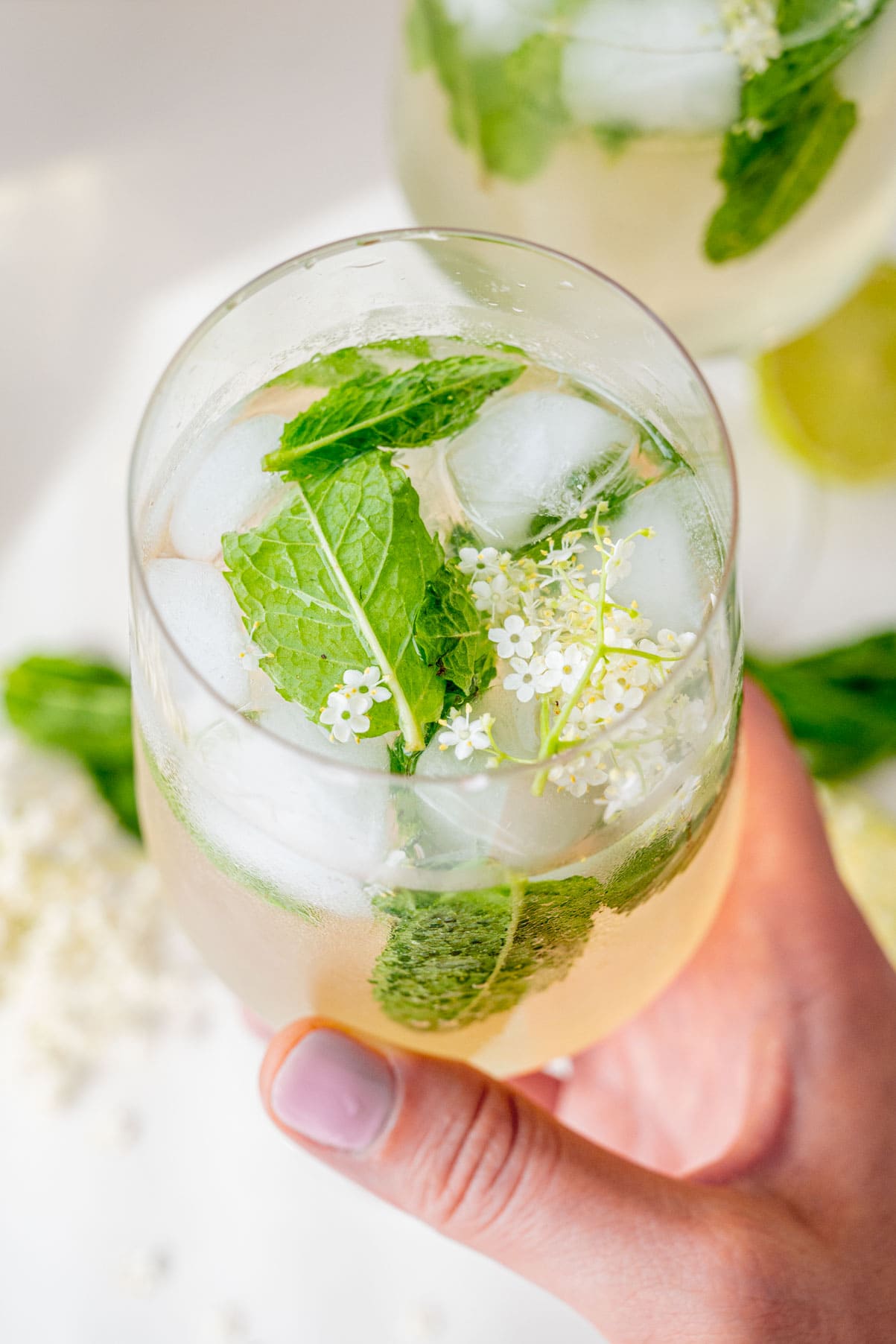 A glass with Hugo Cocktail held in a hand.