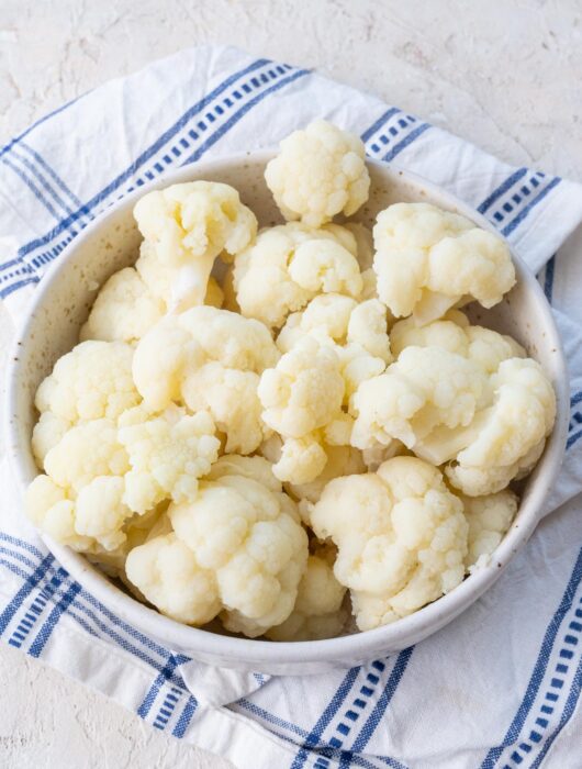 Steamed cauliflower florets in a white bowl.