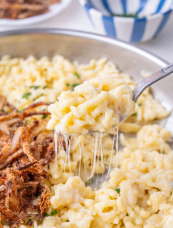 Käsespätzle on a spoon and in a frying pan.