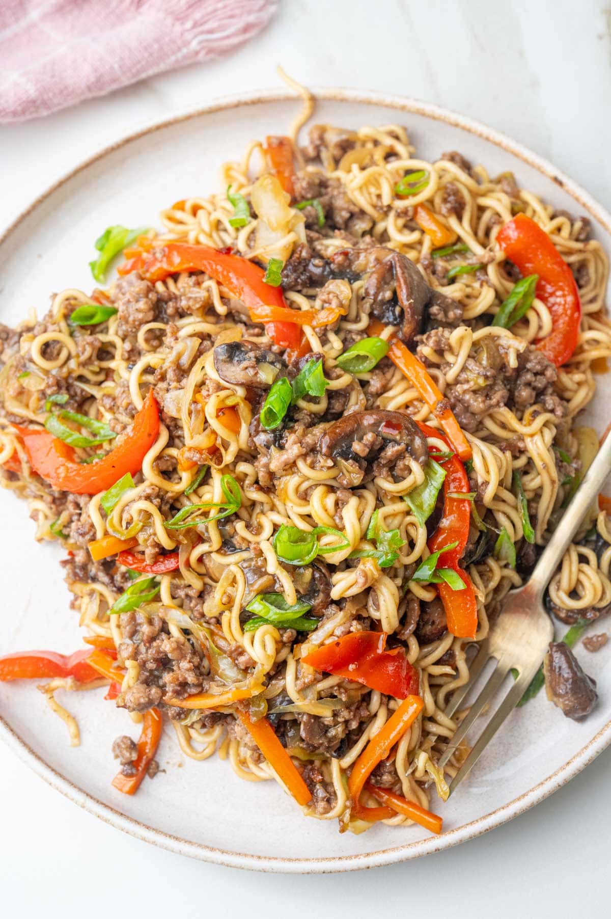 Ground beef noodles with vegetables on a white plate.