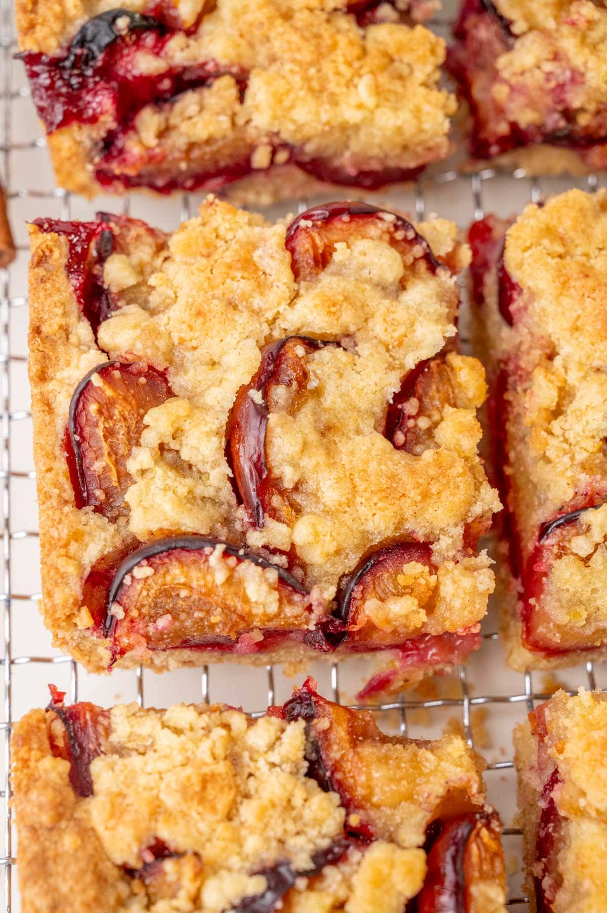 Close-up of a slice of German plum cake with a buttery crumb topping and baked plum halves, showing crisp edges and juicy fruit.