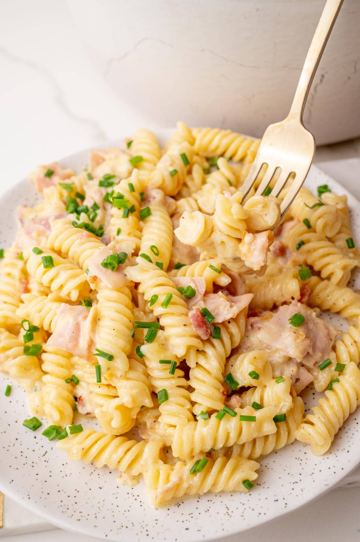 German Schinkennudeln on a white plate, topped with chives.