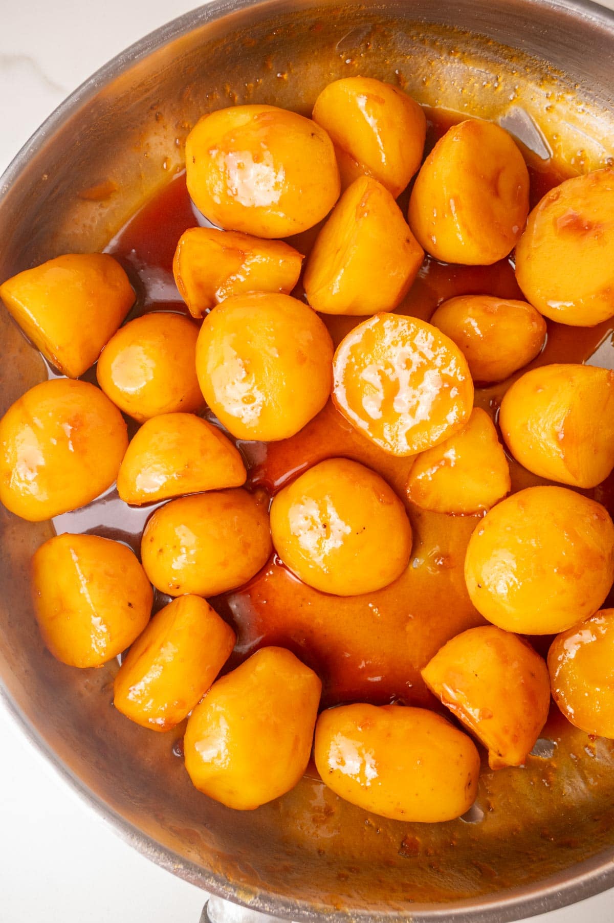Brunede Kartofler in a stainless steel pan.