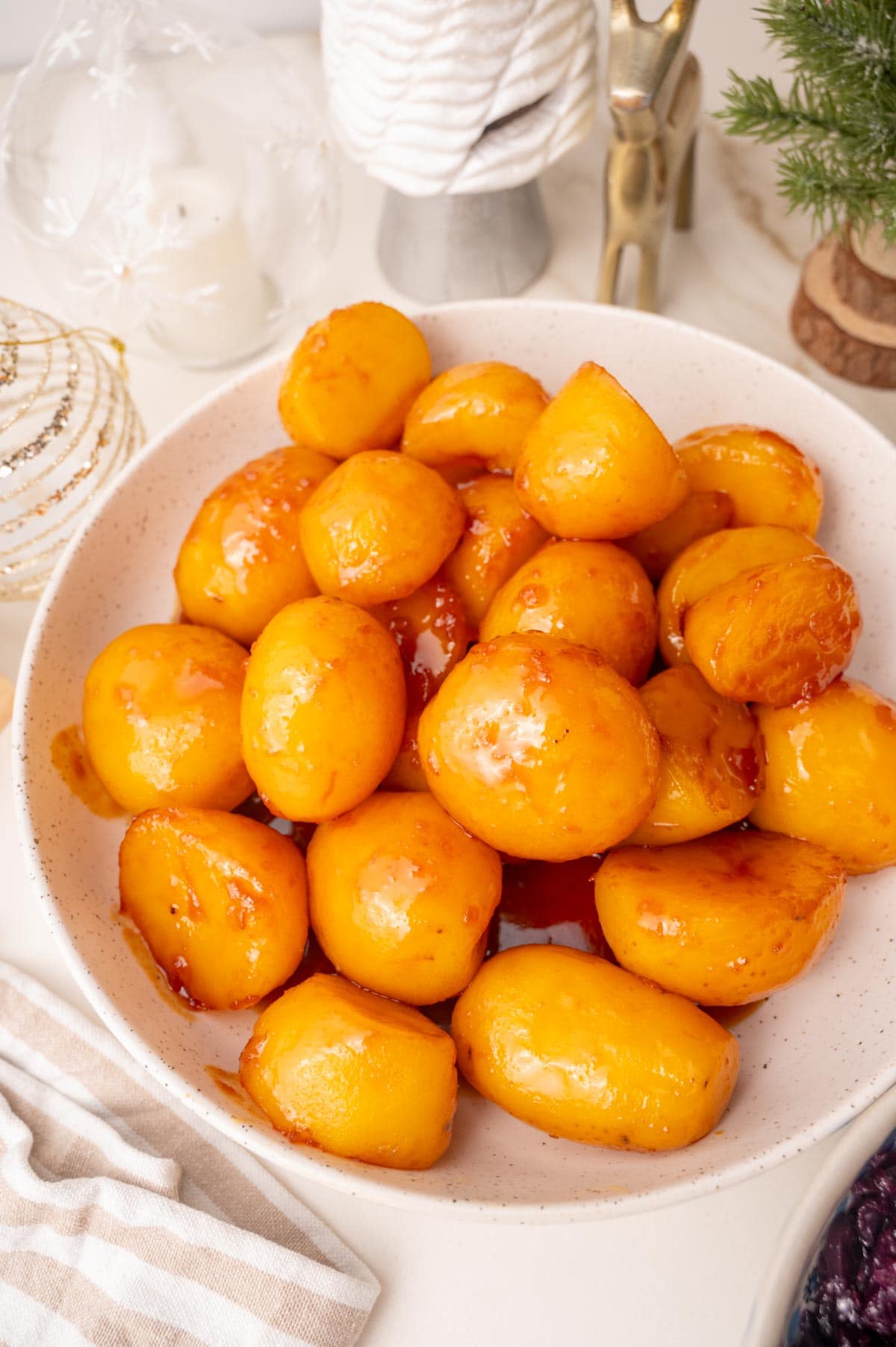 Danish caramel potatoes in a white bowl. Christmas decoration in the background.