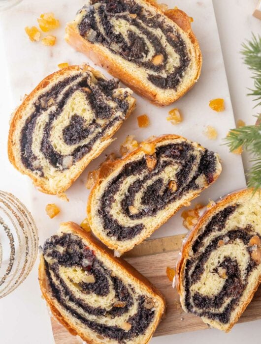 Slices of poppy seed roll on a marble board.