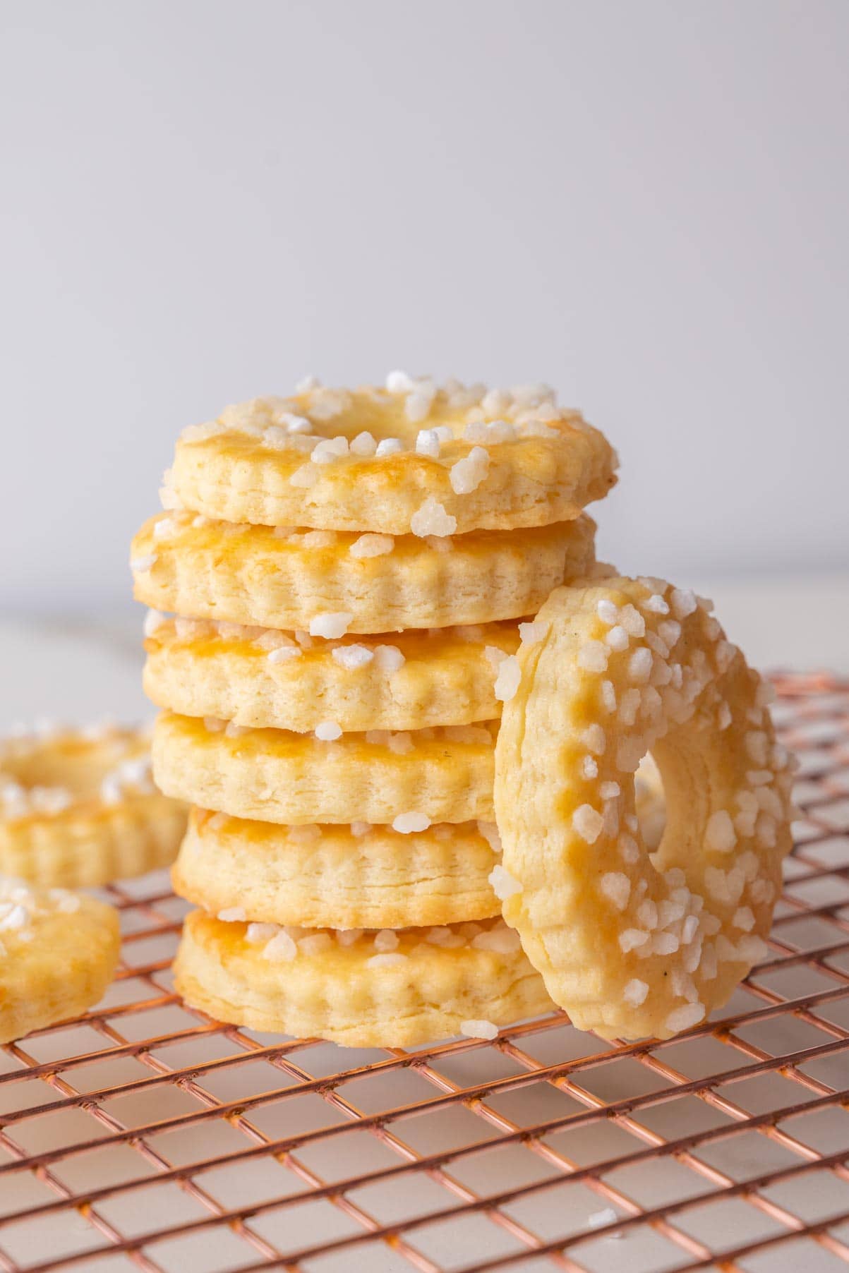 A stack of Saure-Sahne-Kringel (German Sour Cream Cookies) on a gold wire rack.